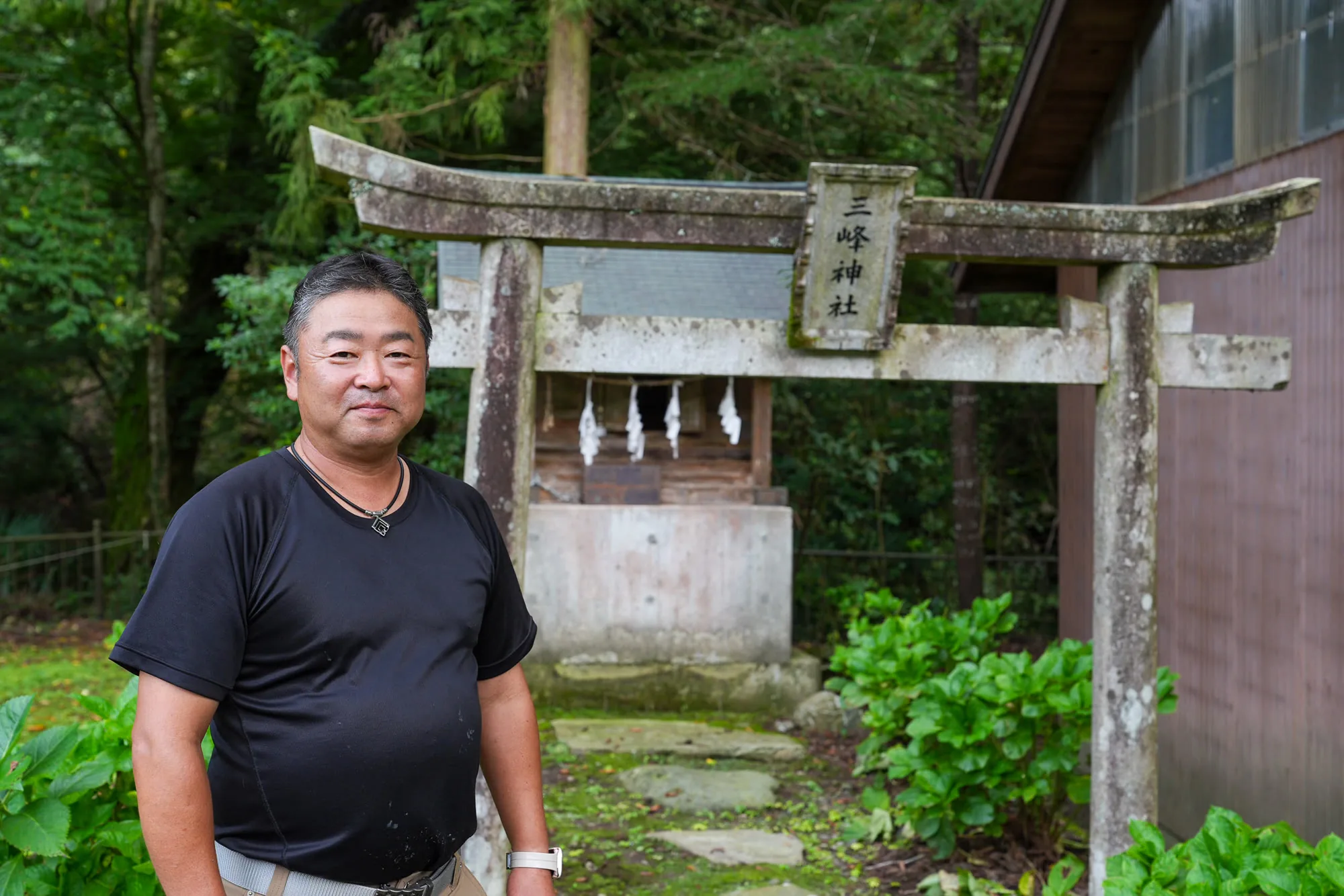三峰神社の前に立つ代表取締役の黒澤秋彦